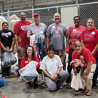 A group of ISU volunteers in a warehouse setting.