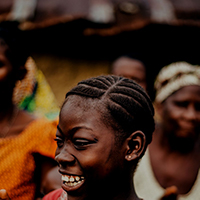 An African girl claps her hands and smiles.