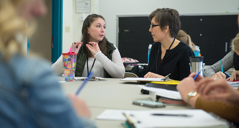 Two female students talking during a class.