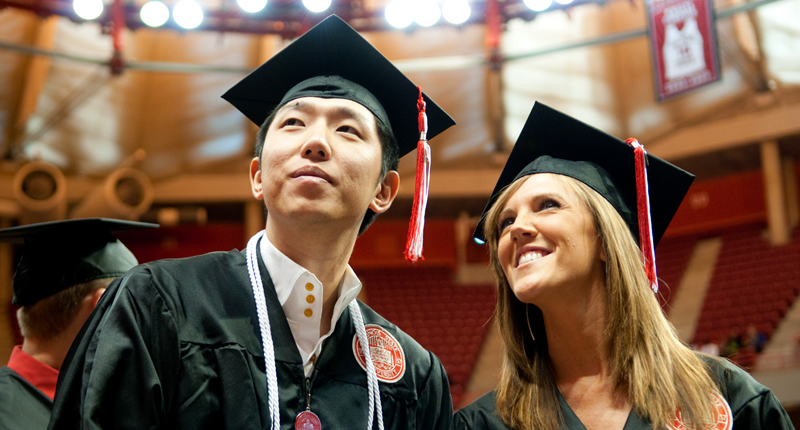 Two students in their caps and gown, ready to graduate.