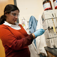 A student wearing safety glasses and gloves while working with lab equipment.
