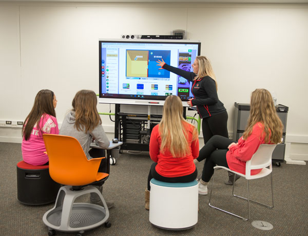 Education students observe their instructor teaching from a monitor.