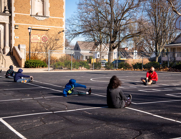 A student PE teacher stretches with his students.