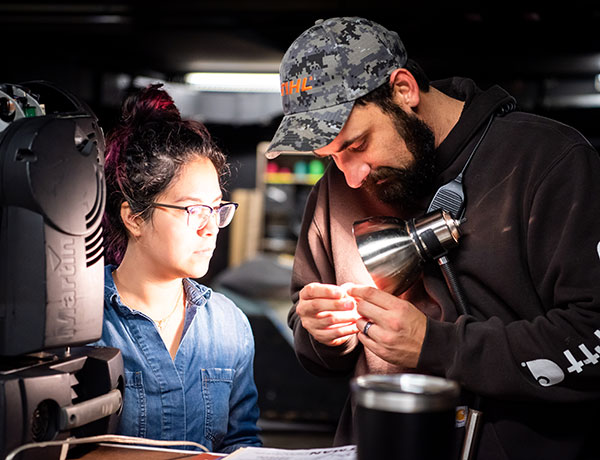 Two lighting design students examine a light fixture.