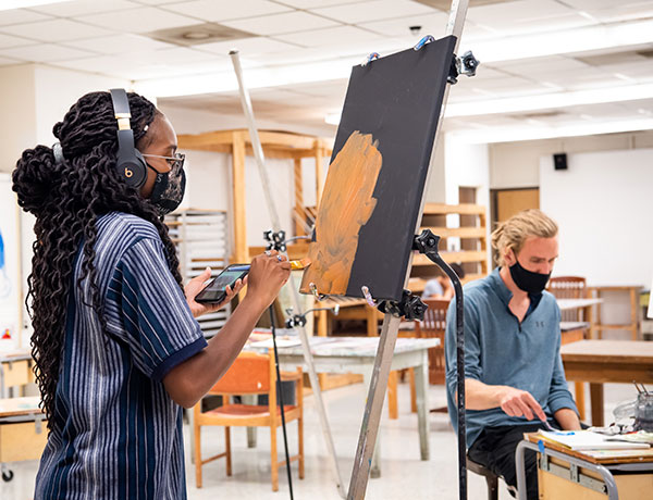 Female student paints on a canvas.