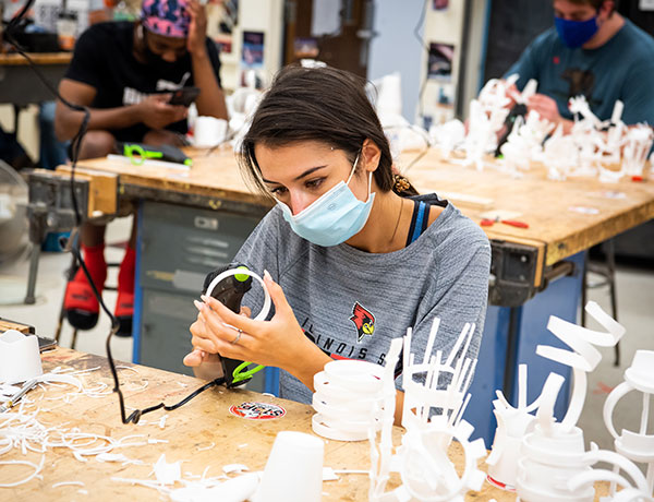Female student uses hot glue to bring her plastic 3D sculptures to life.