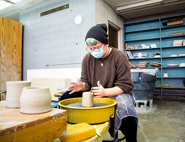 Student uses a potter’s wheel to craft a clay vessel.