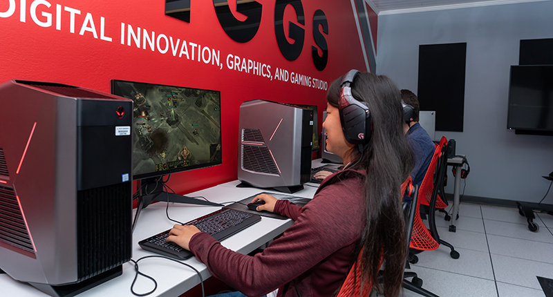 Female student sitting in the DIGGS lab playing a video game.
