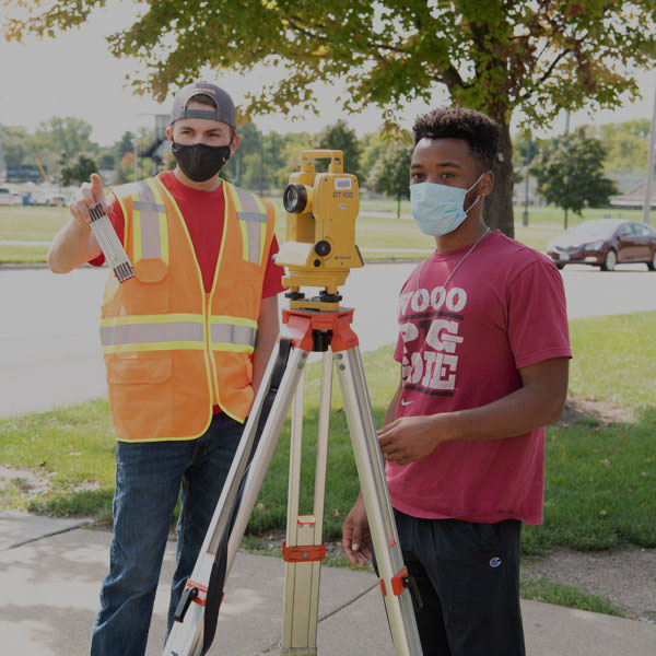 Two Field Engineering students use a sensor outdoors.