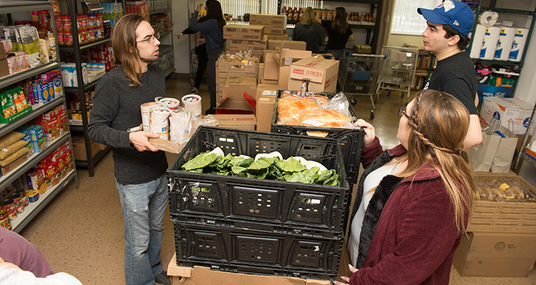 Students organzing boxes of food and crates in a small room.
