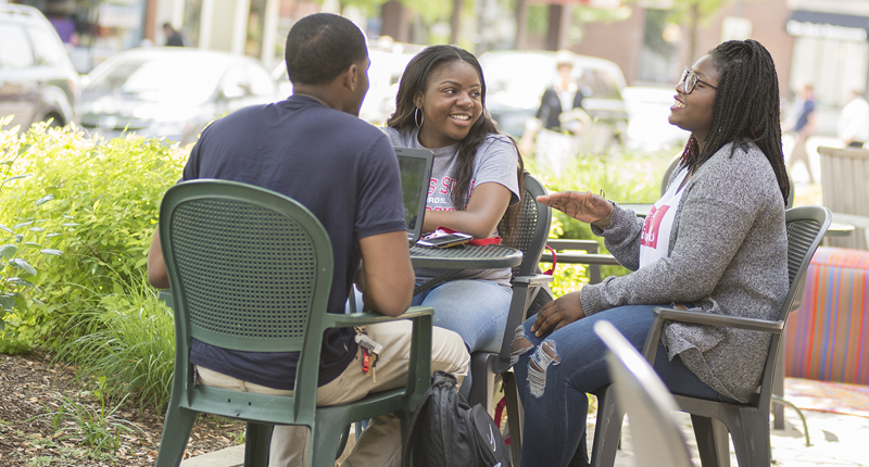 Three students sitting and laughing at a table in Up Town Normal.