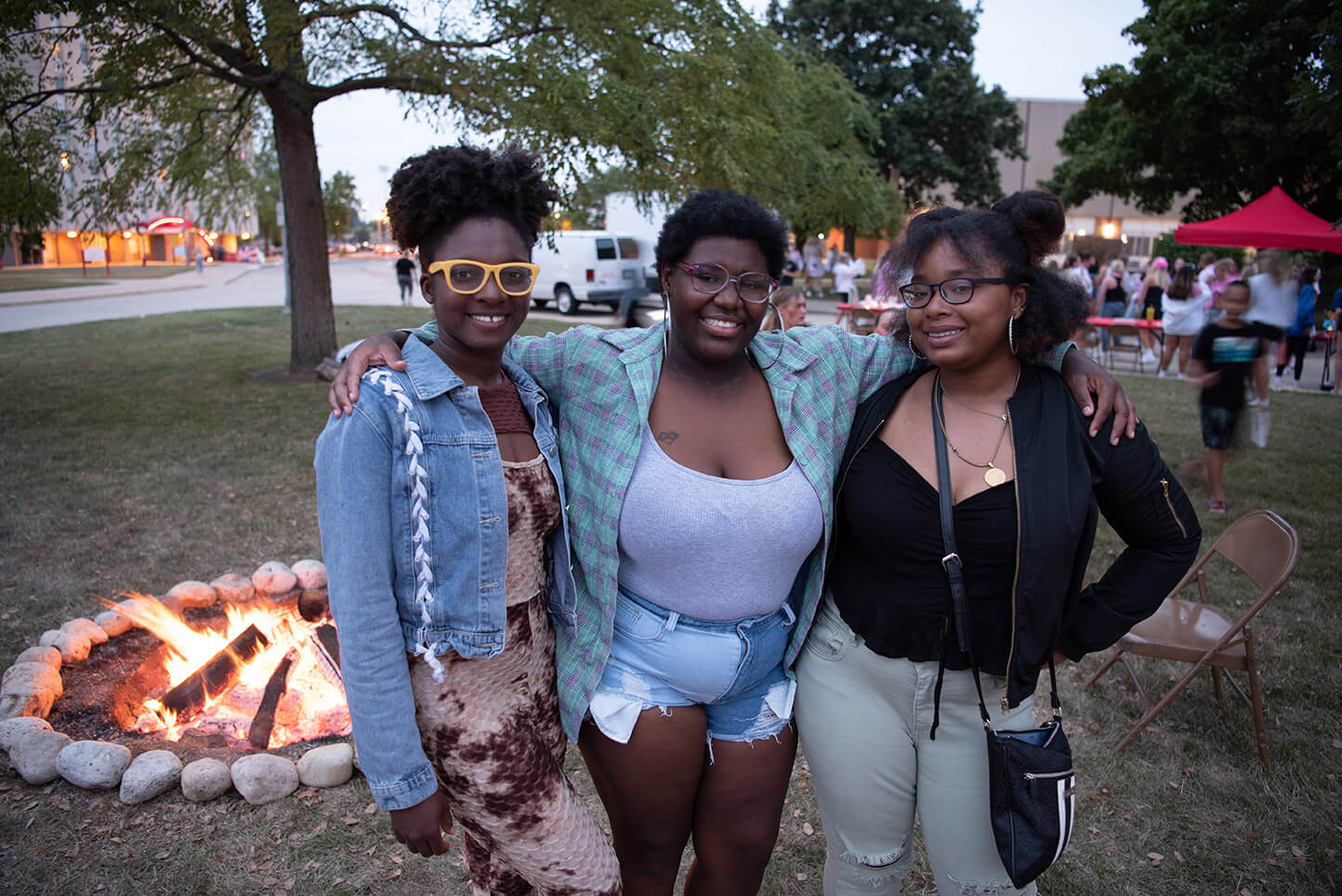 Three friends posing in front of a firepit at the Welcome Week Kickoff.