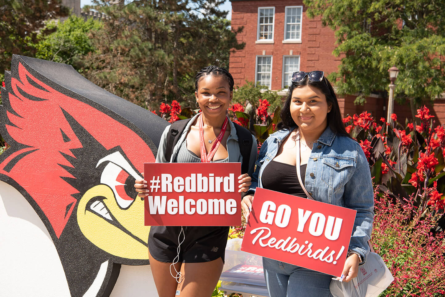 Two students holding '#RedbirdWelcome' and 'Go You Redbirds!' signs at Welcome Week Kickoff.